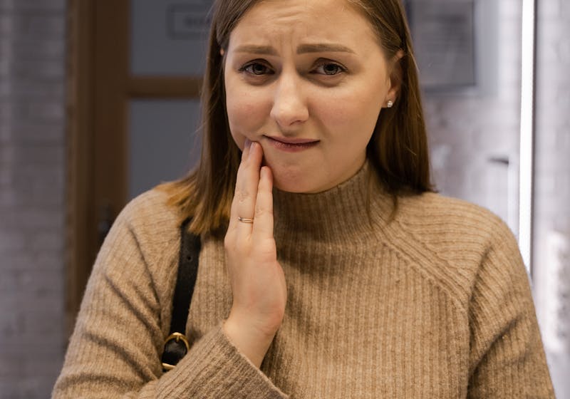 Person holding their cheek with a toothache needing an emergency dentist